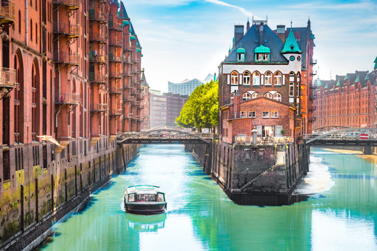 En af Hamborg havns mange kanaler med en lille båd, der passerer, Tyskland