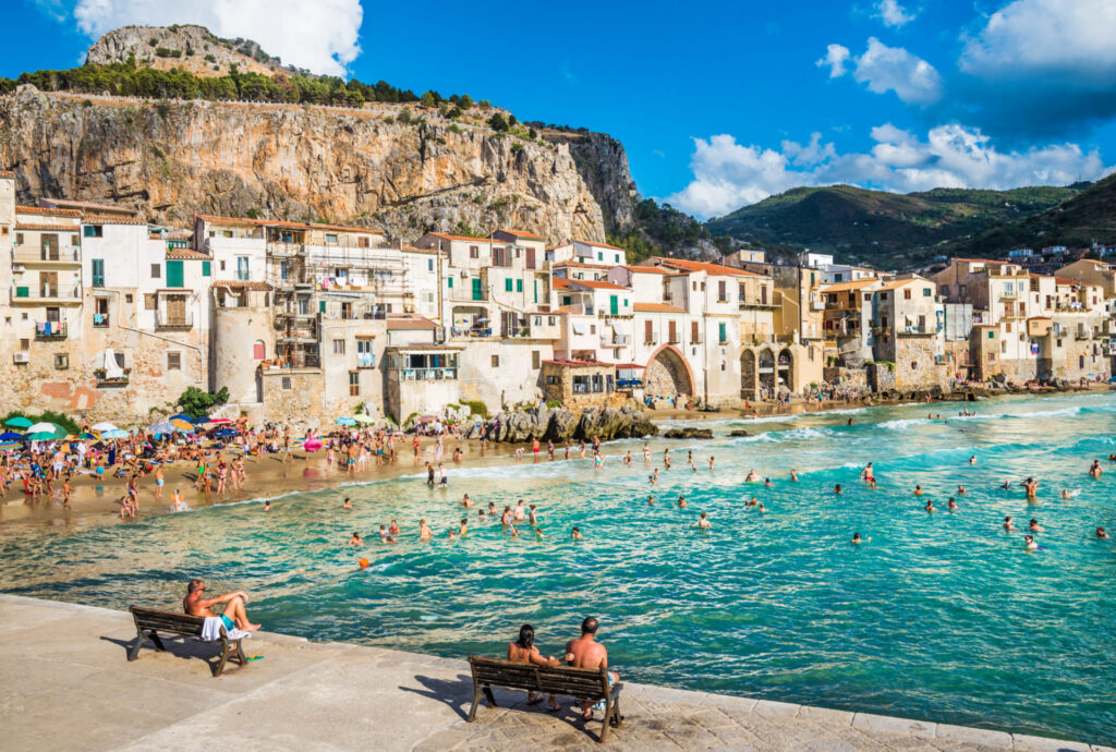 Mennesker slapper af på havnen ved Cefalu i Sicilien