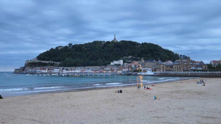 La Concha-stranden i San Sebastián i aftenlys med Monte Urgull og havnen i baggrunden